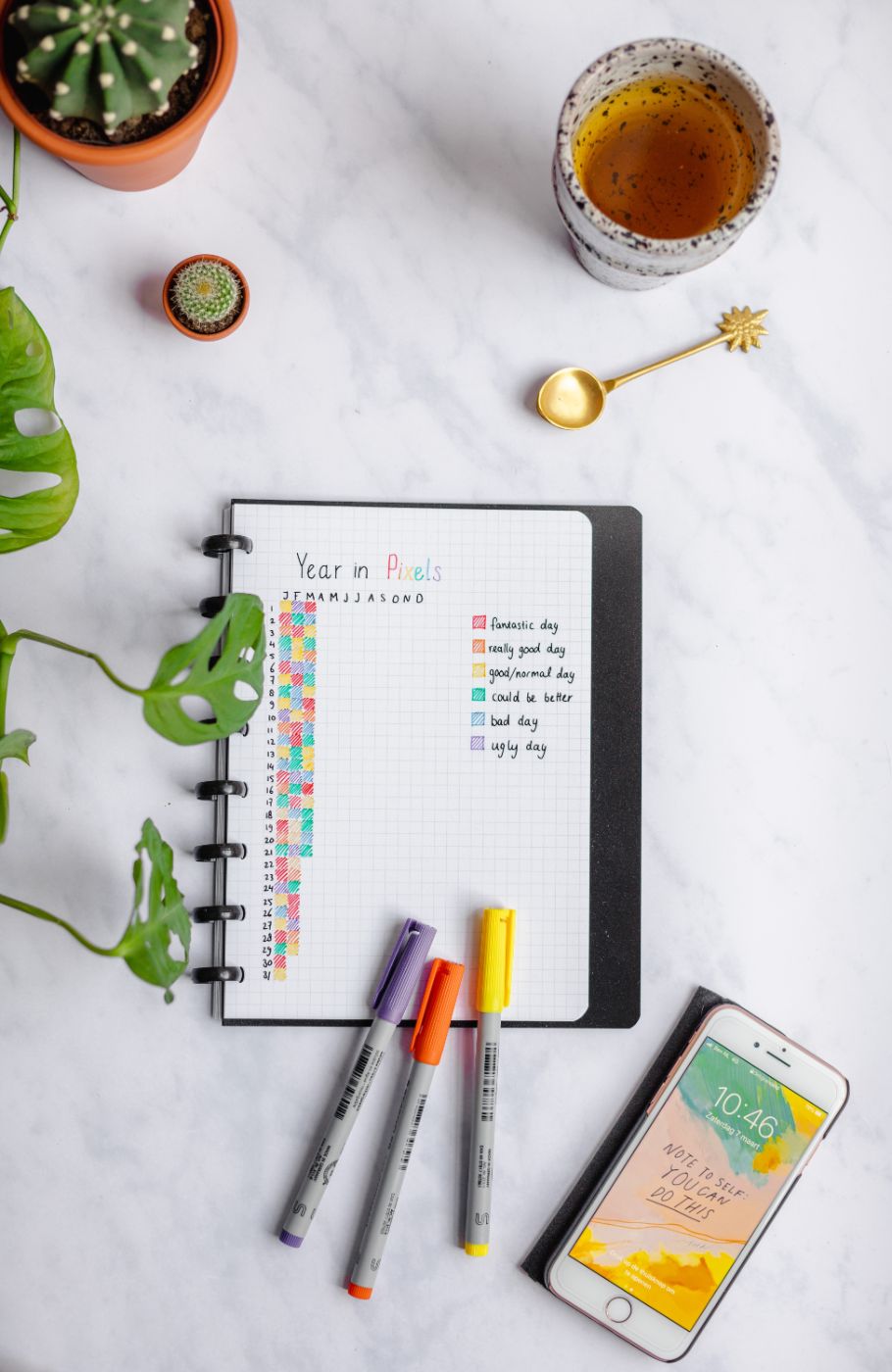 Erasable notebook with a 5x5 mm grid page surrounded by assorted items on marble background