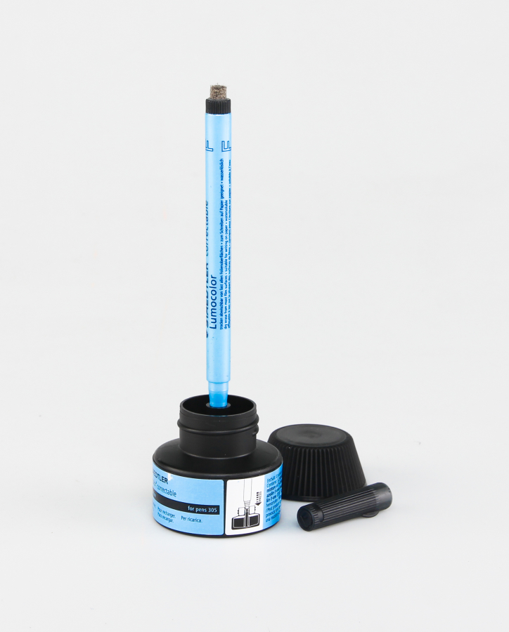 Pen standing upright in black ink refill station on grey background