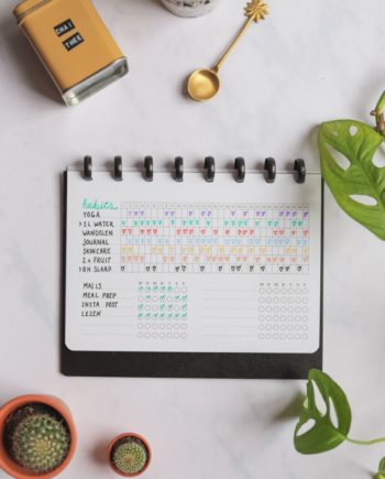 Erasable habit tracker next to assorted items on marble background